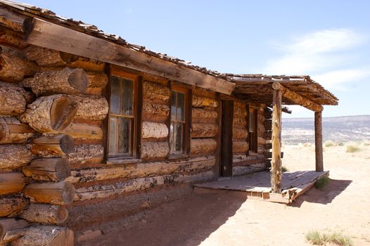 Close up of a rustic 'wild west' style log cabin against a blue sky and desert with copy space.