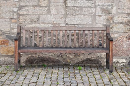Old wooden bench against ancient stone wall.