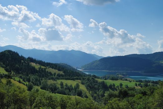 Mountain landscape with green fields and lake behind