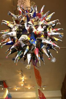 Spiky multicolored pinata hanging from a ceiling with colored streamers