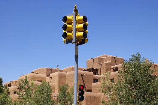 New Mexican Adobe Building, against a deep blue sky, featuring a yellow stop light in the middle of the frame, with copy space.