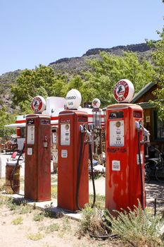 Three old fashioned, vintage red fuel (gas/ petrol) pumps, in a row, outdoors.