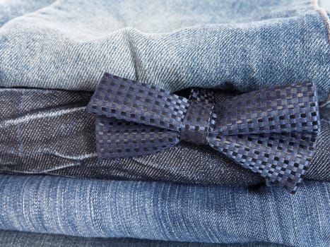 heap of jeans and decorative tie as a fashion background