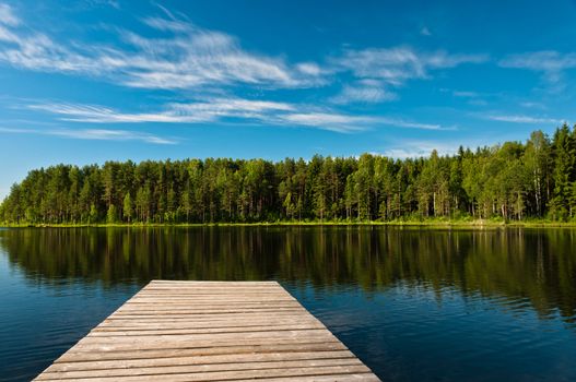 Wooden pier on lake scene, horizontal view with cloudscape on background