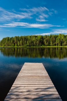 Wooden pier on lake symmetrical scene, vertical view with forest