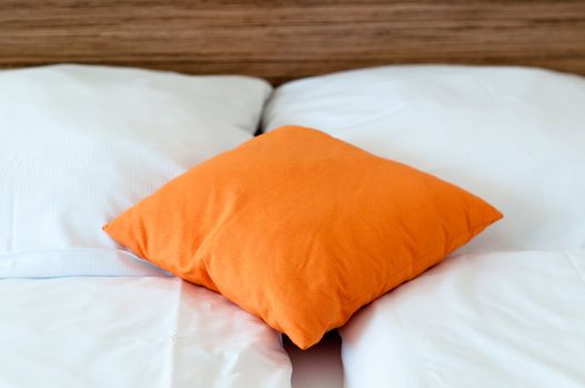 Orange pillow on a bed in a hotel room