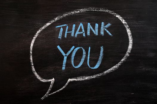 Thank you written in a speech bubble with blue chalk on a smudged blackboard