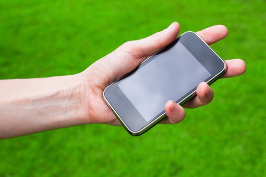 Mobile phone in the hand    on background of green grass