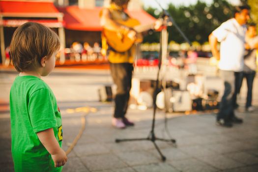 Young boy listening to musicians in old Montreal