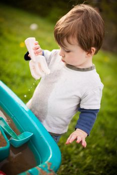 Young boy playing outside in the sand and water