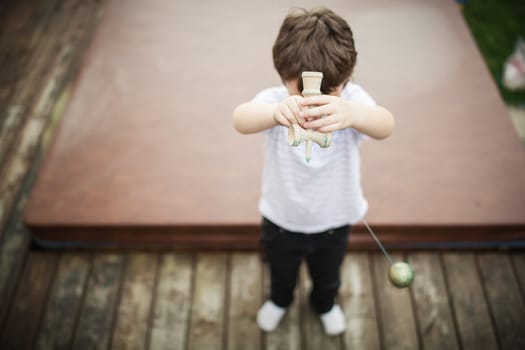 Boy playing cup and ball outside on a patio