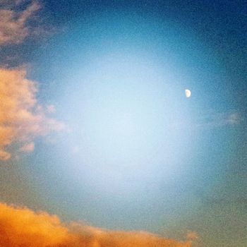 an early evening moon in the clear sky