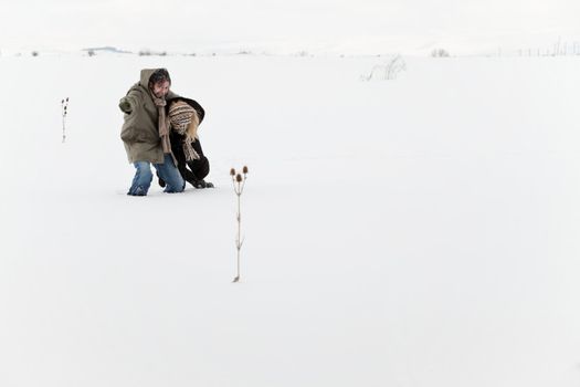 Struggling lost couple, embracing and walking on winter snow field