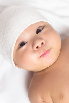 A cute little baby is wearing a white hat is making funny face. 
