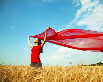 Teen girl at a wheat field with red fabric