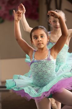 Cute little girls in ballet dresses practice in a studio
