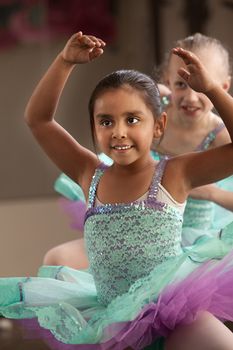 Children in ballet dresses practice dance moves