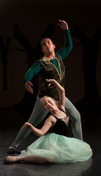 Young ballet dancers performing over dark background