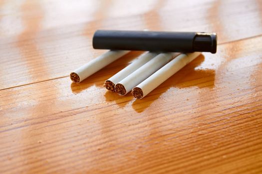 Four cigarettes and lighter on the lacquered wooden table