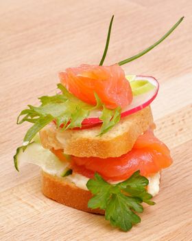 Appetizer of Smoked Salmon with Radish, Cucumber and Greens isolated on wooden background