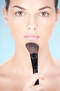 Portrait of a pretty young woman holding powder brush