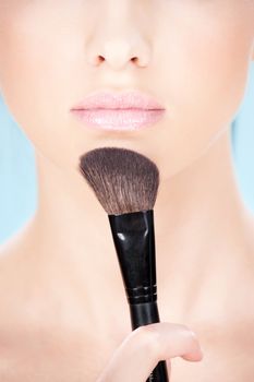 Part of a woman's face and makeup brush