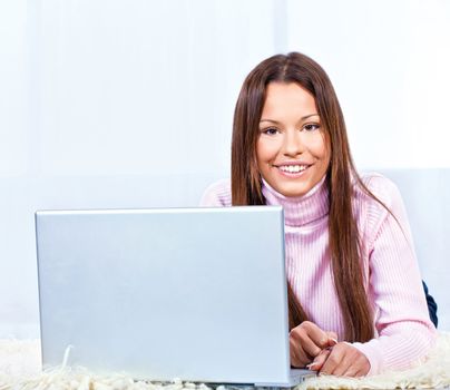 Pretty young woman with laptop on carpet at home