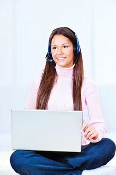 Pretty young woman with headphones and  laptop at home