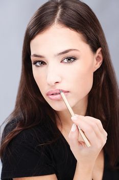 Woman applying cosmetic pencil on her lips