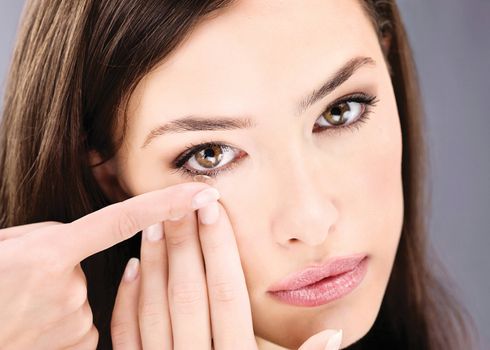 Close up of a woman putting contact lens in her eye