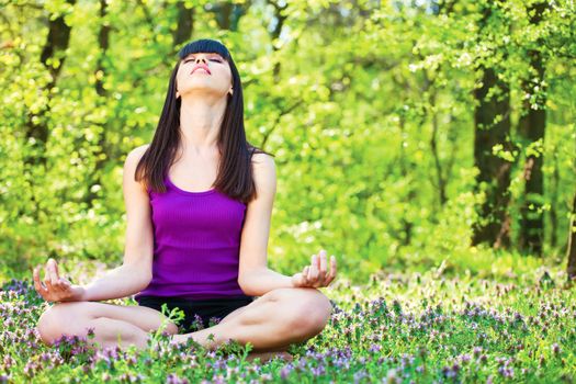 Young woman in lotus pose at the meditation in forest