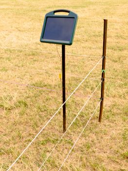 Solar electric fence charger mounted on a pole providing the energy for electrical livestock fencing out on rural farmland