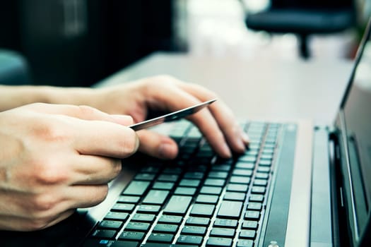 Close-up of human hands with credit card on keyboard