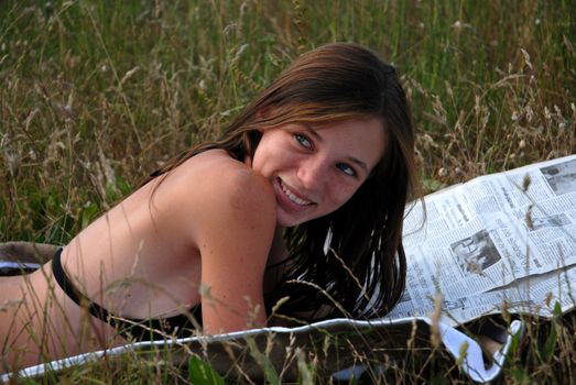 young teenage reading newspaper in the grass