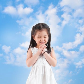 East Asian girl making a wish with smiling, blue sky as background