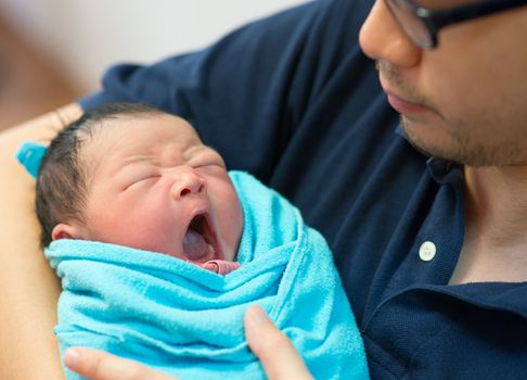 Asian father and newborn baby girl in hospital