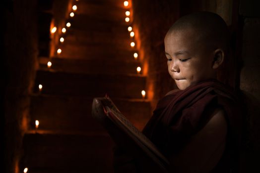 Little monk reading book inside monastery