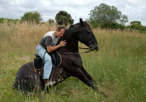 man and his sitting horse in a field