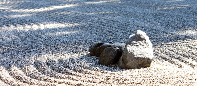 Zen stone garden wih a center rock and shadows