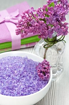 Sea-salt  and a bouquet of lilacs on a wooden background 
