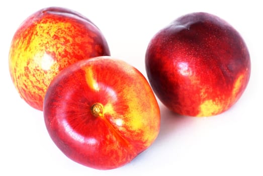 three appetizing ripe red nectarines over white background