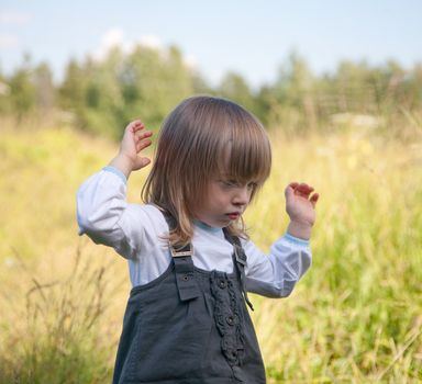 The little girl on summer meadow stretches a hand