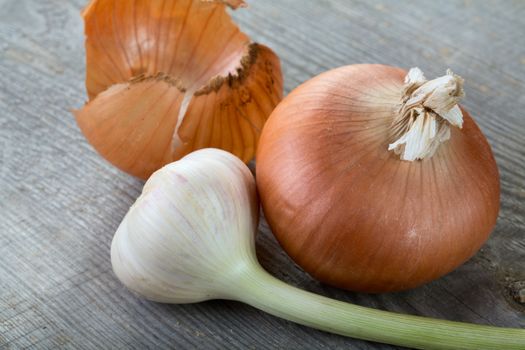Garlic and onions with  peel on a table from unplaned boards