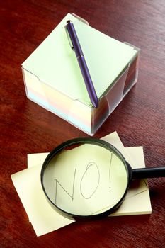 Magnifier and pile of stickers with an inscription "no" on a table