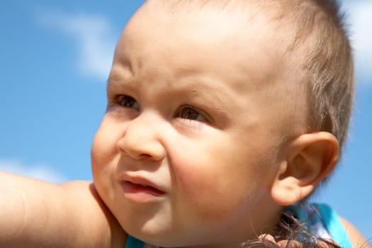Portrait of the little boy close up against  blue sky