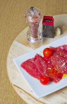 Red carpaccio with tomatoes over a white plate