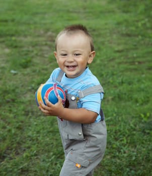 The little boy plays with  ball on green grass