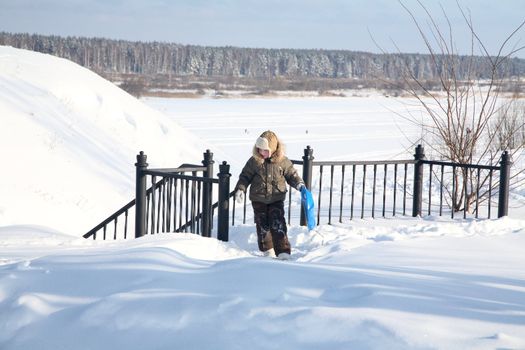 boy with a sledge walks upstairs in the winter afternoon