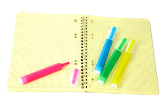 Markers and writing-book with a spiral on  white background