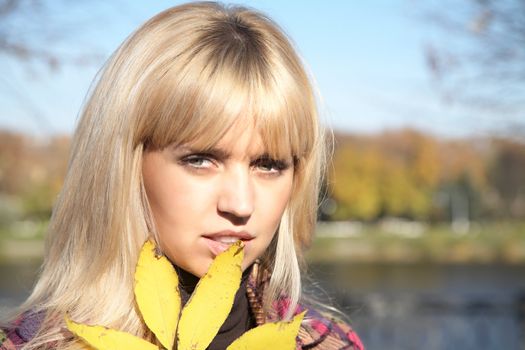 Portrait of the girl with yellow leaf in the autumn afternoon